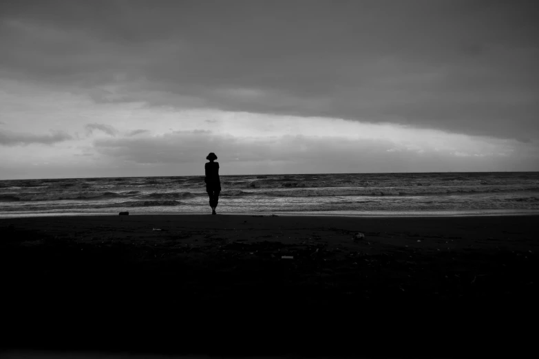 a man standing in front of the ocean under clouds