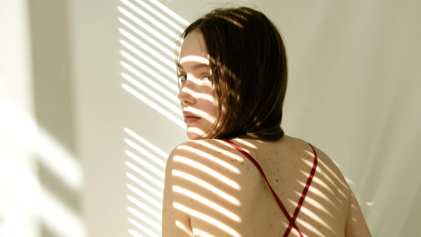 woman standing in front of wall looking out with white blinds