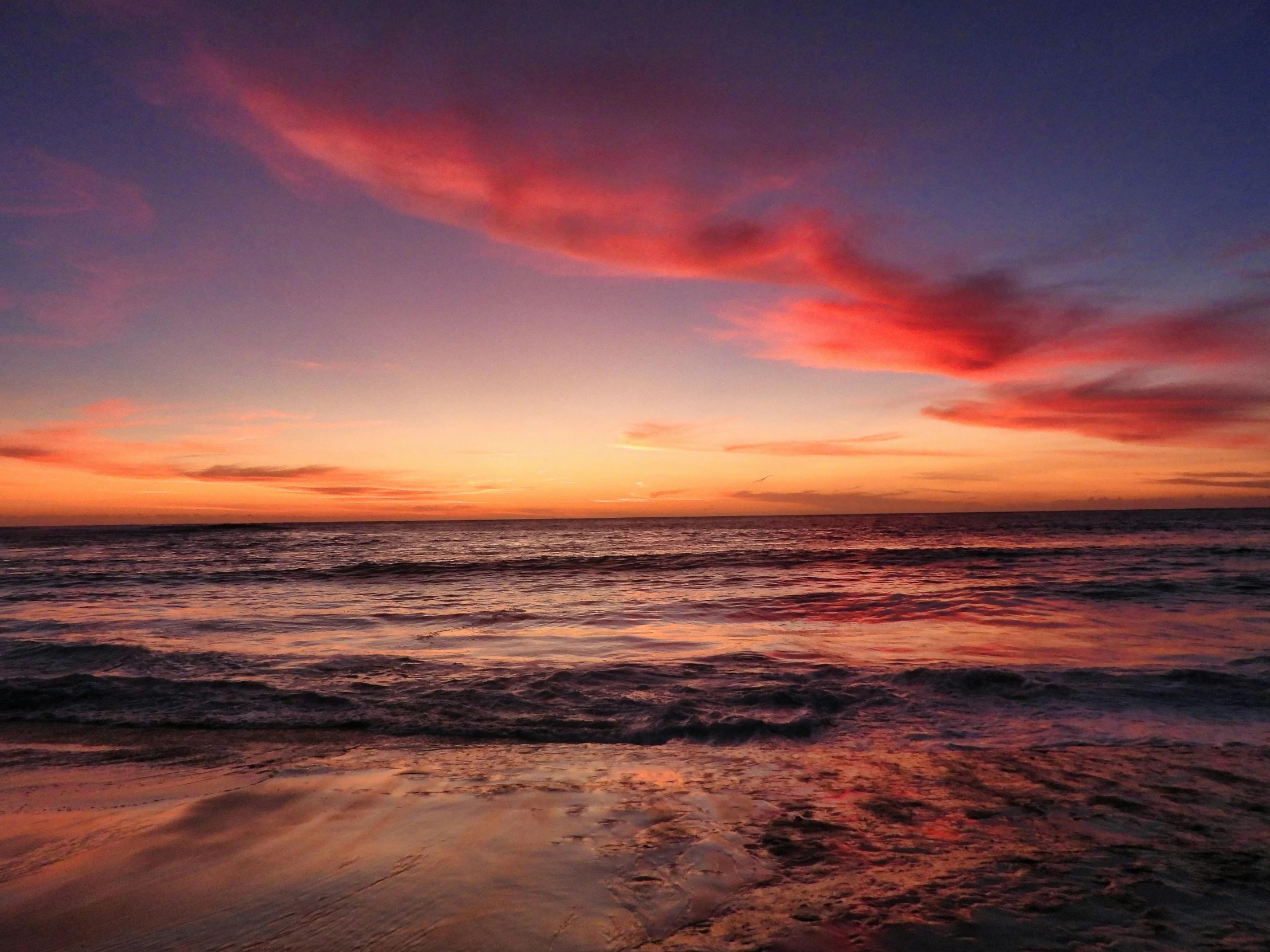 the sun sets on a beautiful beach by some water