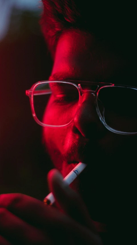 a man in glasses is smoking a cigarette