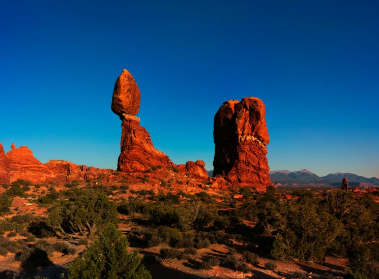 two large rocks on a plain and some trees