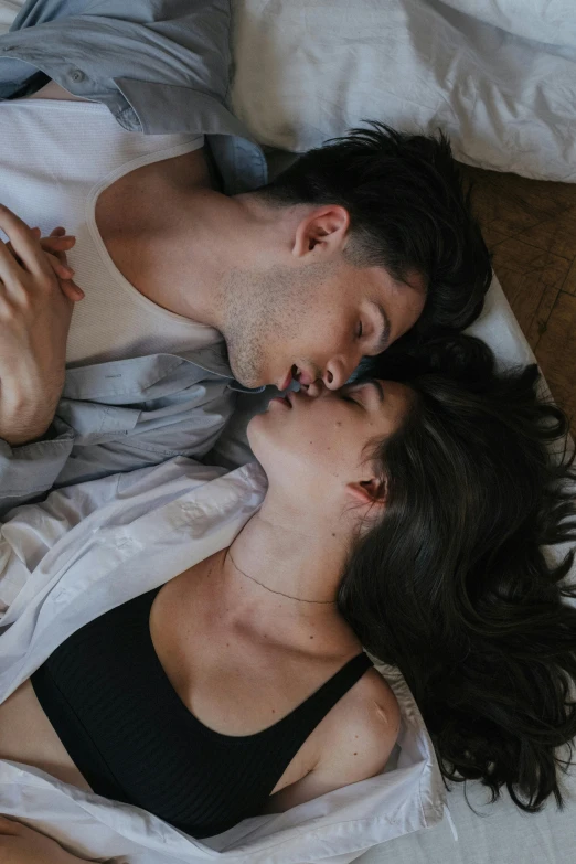 a man and woman laying in bed kissing