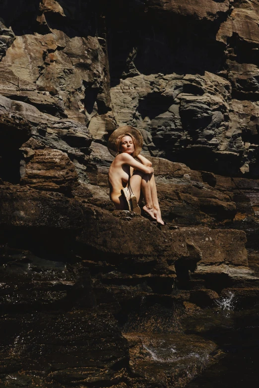 a young  girl is sitting on rocks