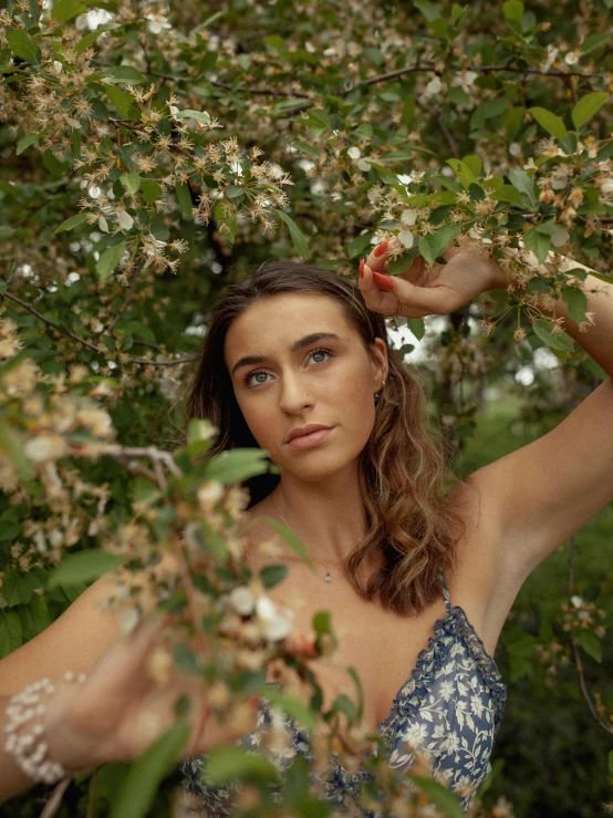 a woman standing in front of a tree with flowers on it