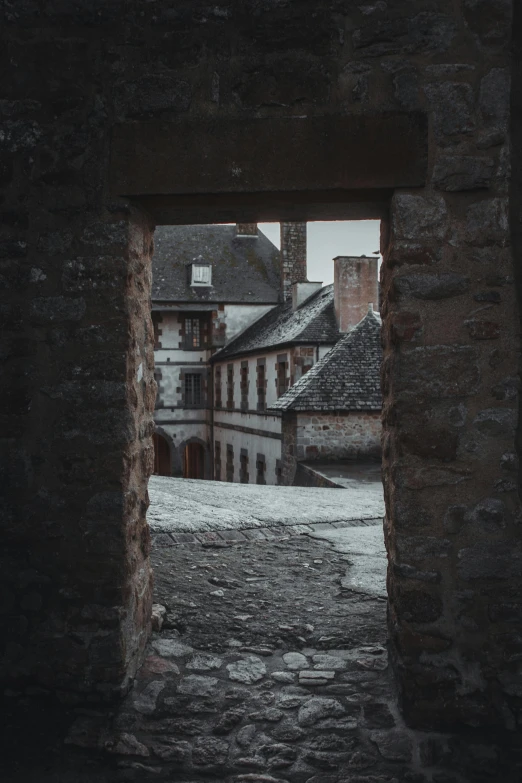 through the archway to an old building that has stone steps and a brick wall is shown