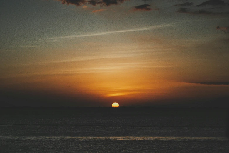 a sunset over the ocean with a body of water in the foreground