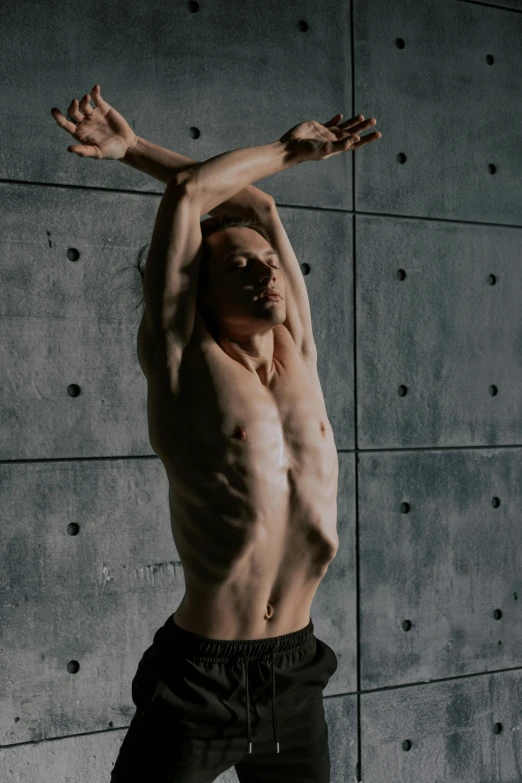 a shirtless man stretching with his hands spread
