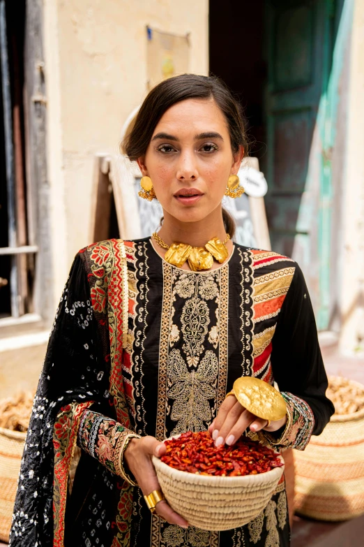 a woman wearing a necklace holding a basket filled with beans