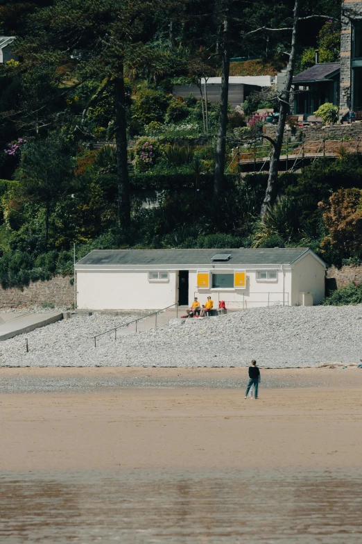 people walk on the beach beside some buildings