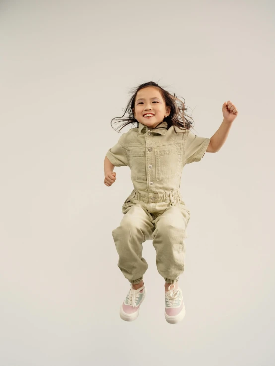 a little girl jumping in the air while wearing a suit