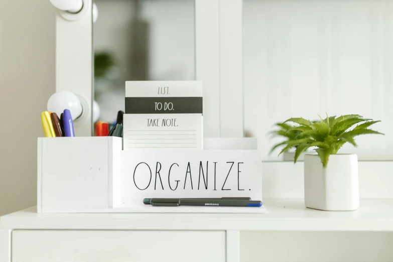 a desk with a pen, notes and plant on it