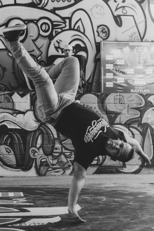 a man doing a handstand in front of a grafitti wall