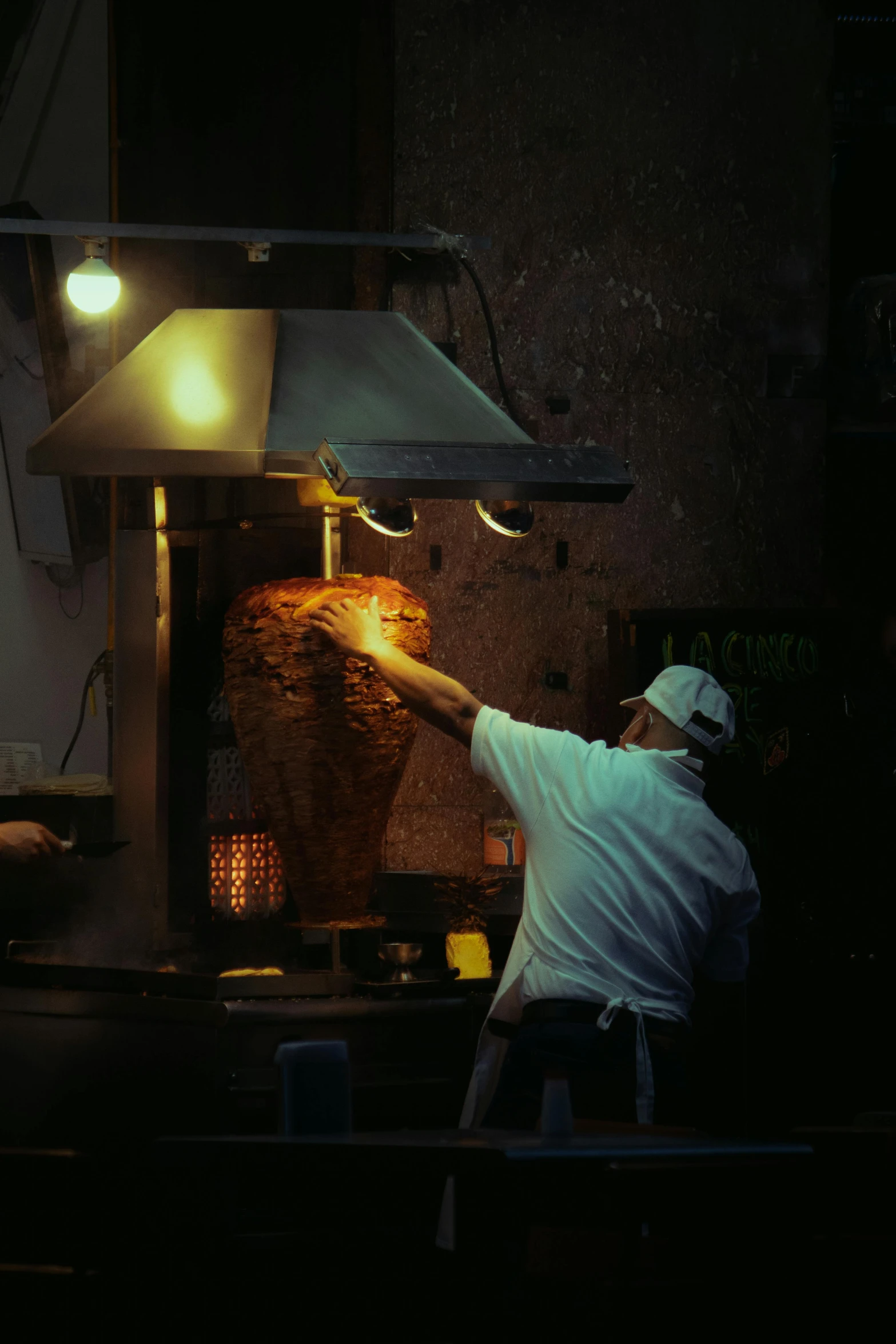 man in hat placing bread into a stone oven