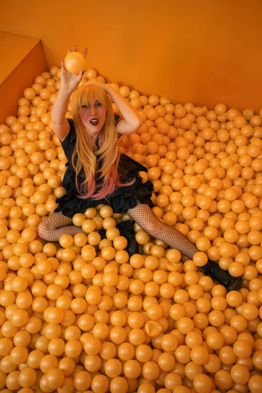 a woman is sitting in a ball pit full of oranges