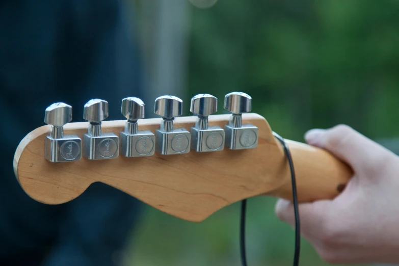 a small guitar being held by a person with earbuds