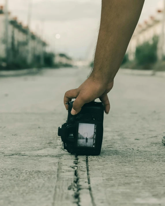 person holding a small digital camera on the road