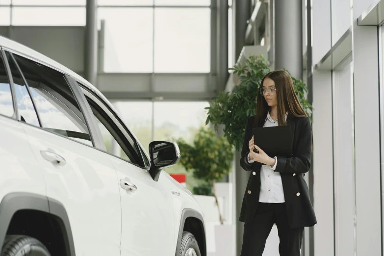 a business woman is holding a clip board and standing near a car