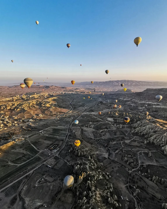 a big bunch of  air balloons flying over a valley