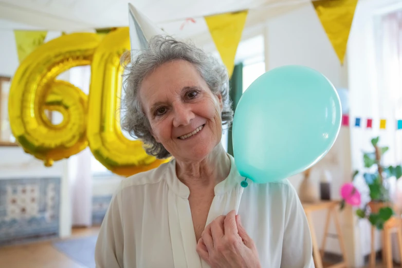 an elderly woman smiles as she holds a balloon