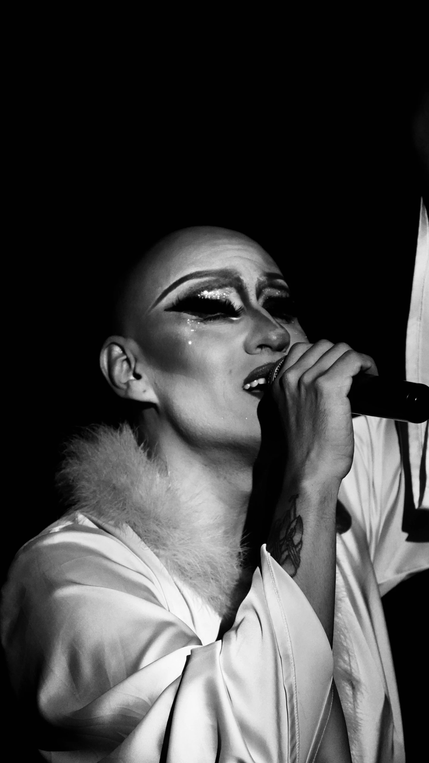 black and white pograph of a woman in makeup singing