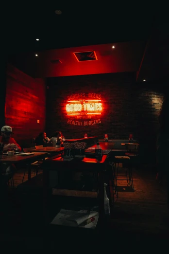 a restaurant sign in the dark next to red lit tables