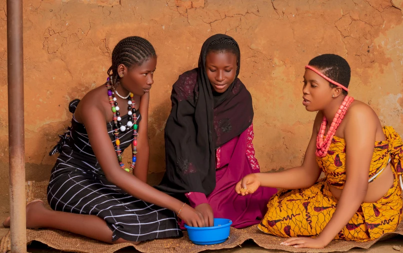 three women sit and talk in front of a wall