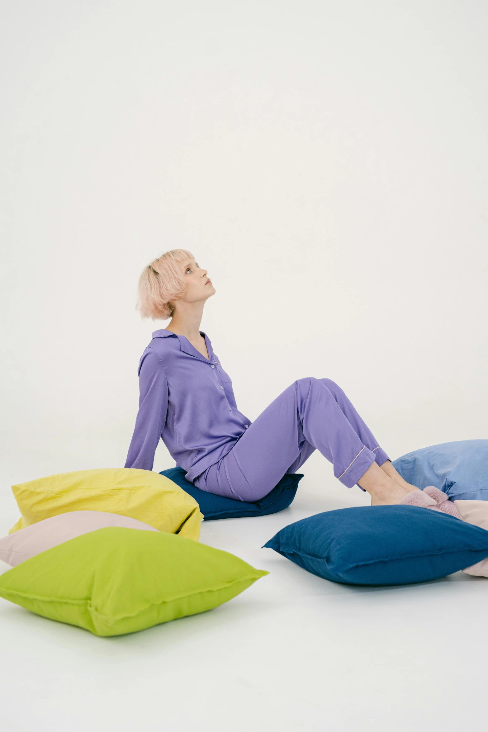 there is a woman sitting on the ground wearing different colored pillows