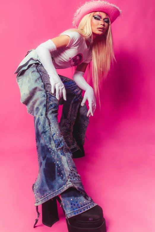 a model poses with her feet on her hips wearing jeans and pink head covering