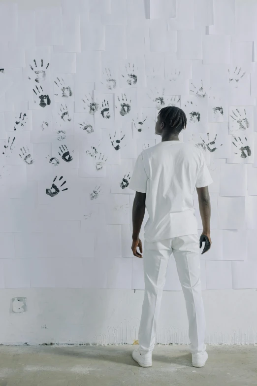 a man looks at several hand prints on a wall