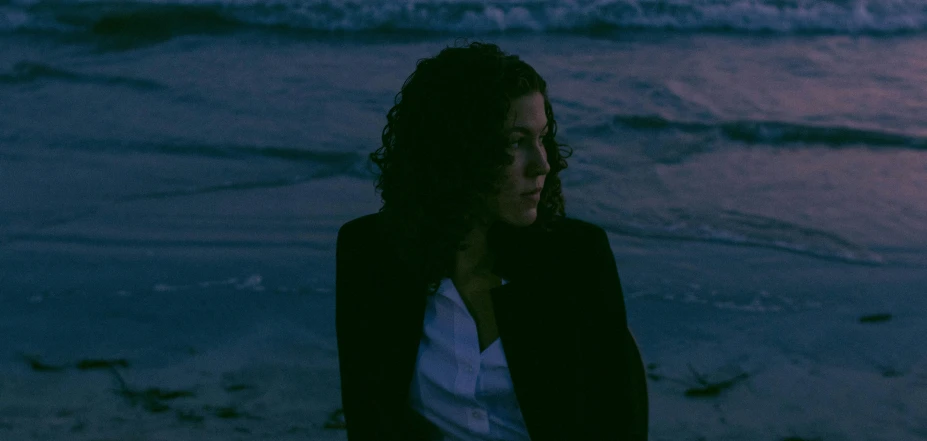 a woman is standing at the beach with a frisbee in her hand