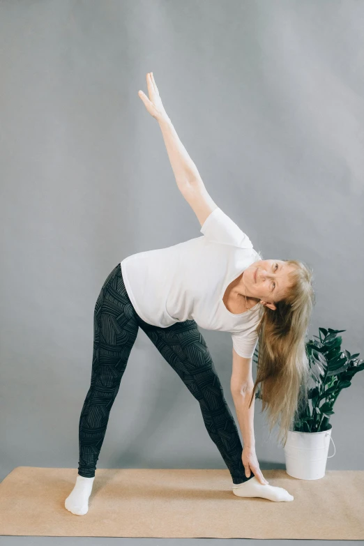 woman doing yoga pose in white shirt and black pants