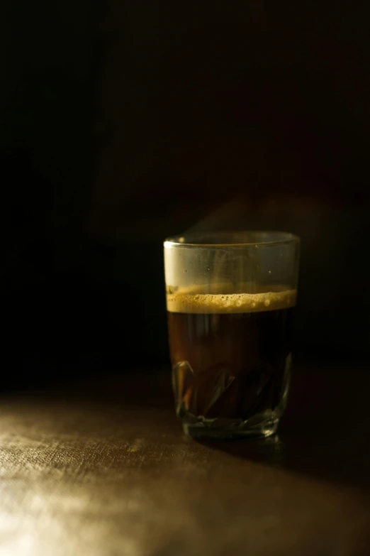 a glass cup of beer with a light coming from the side