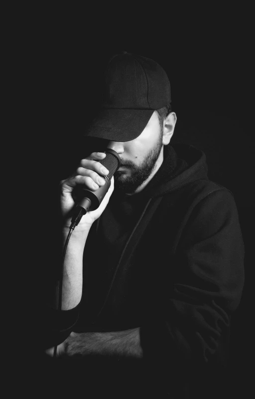 a man in black shirt and hat holding up microphone