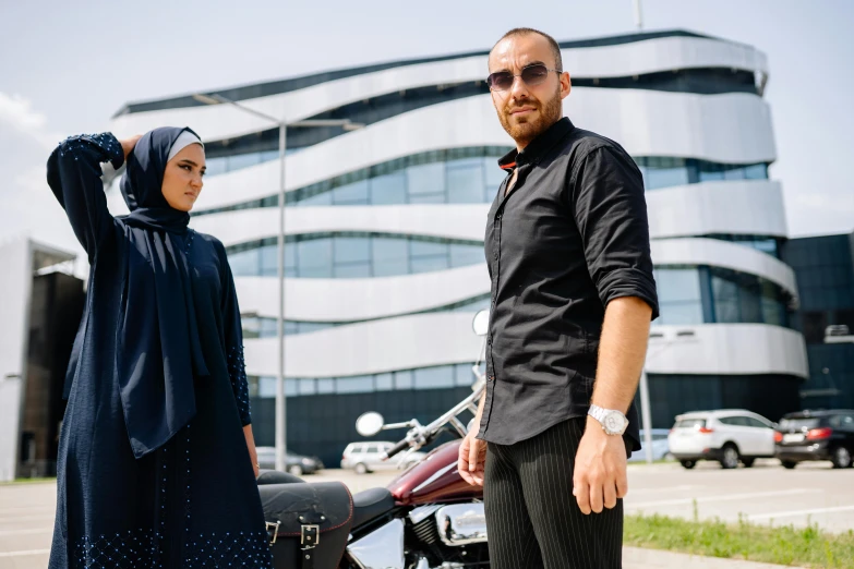 a man and woman standing next to a motorcycle