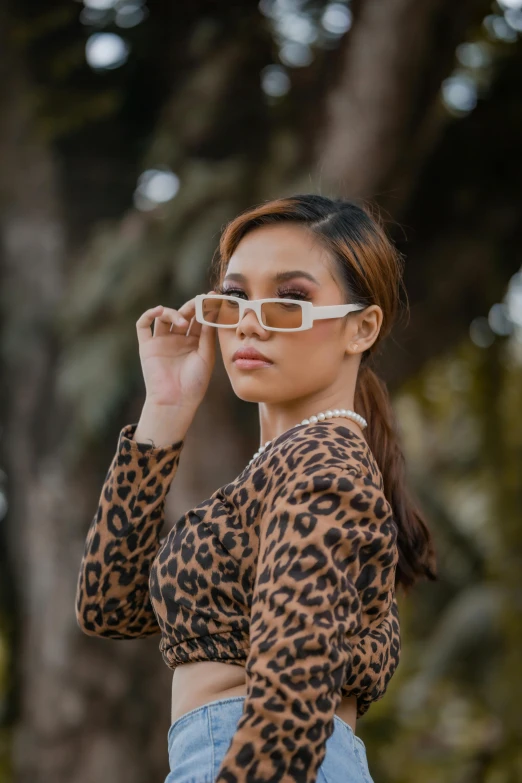 a woman wearing glasses standing by a tree