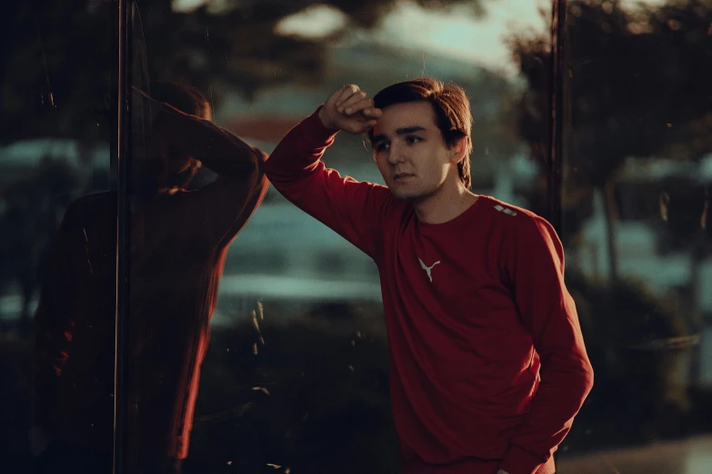 young male standing near a wall with trees in the background