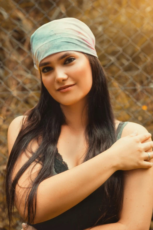 a woman with long hair and blue headband posing in front of a chain link fence