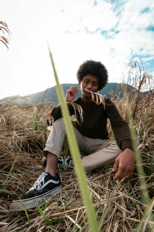 a young man sitting on the ground with a toothbrush in his mouth