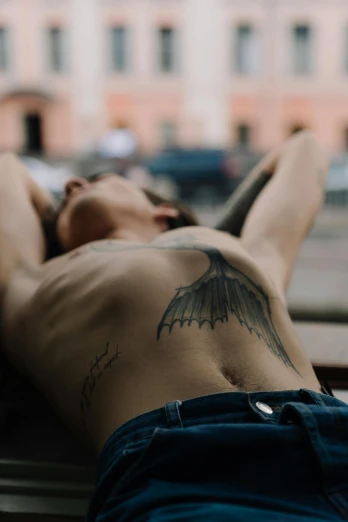 a man with an eagle tattoo lies on his back
