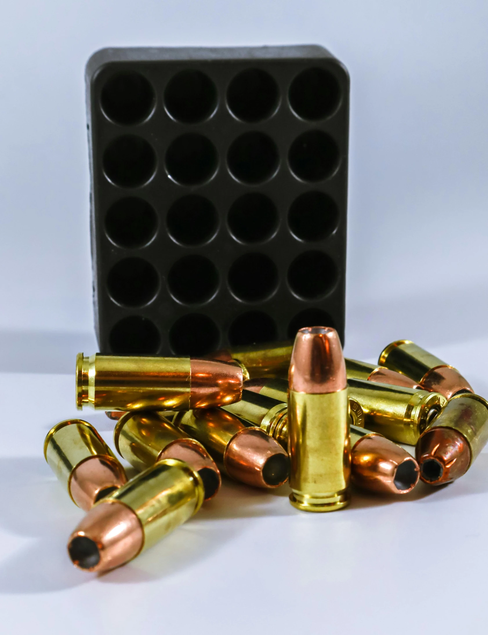 the cartridges of a rifle sit beside a black plastic box