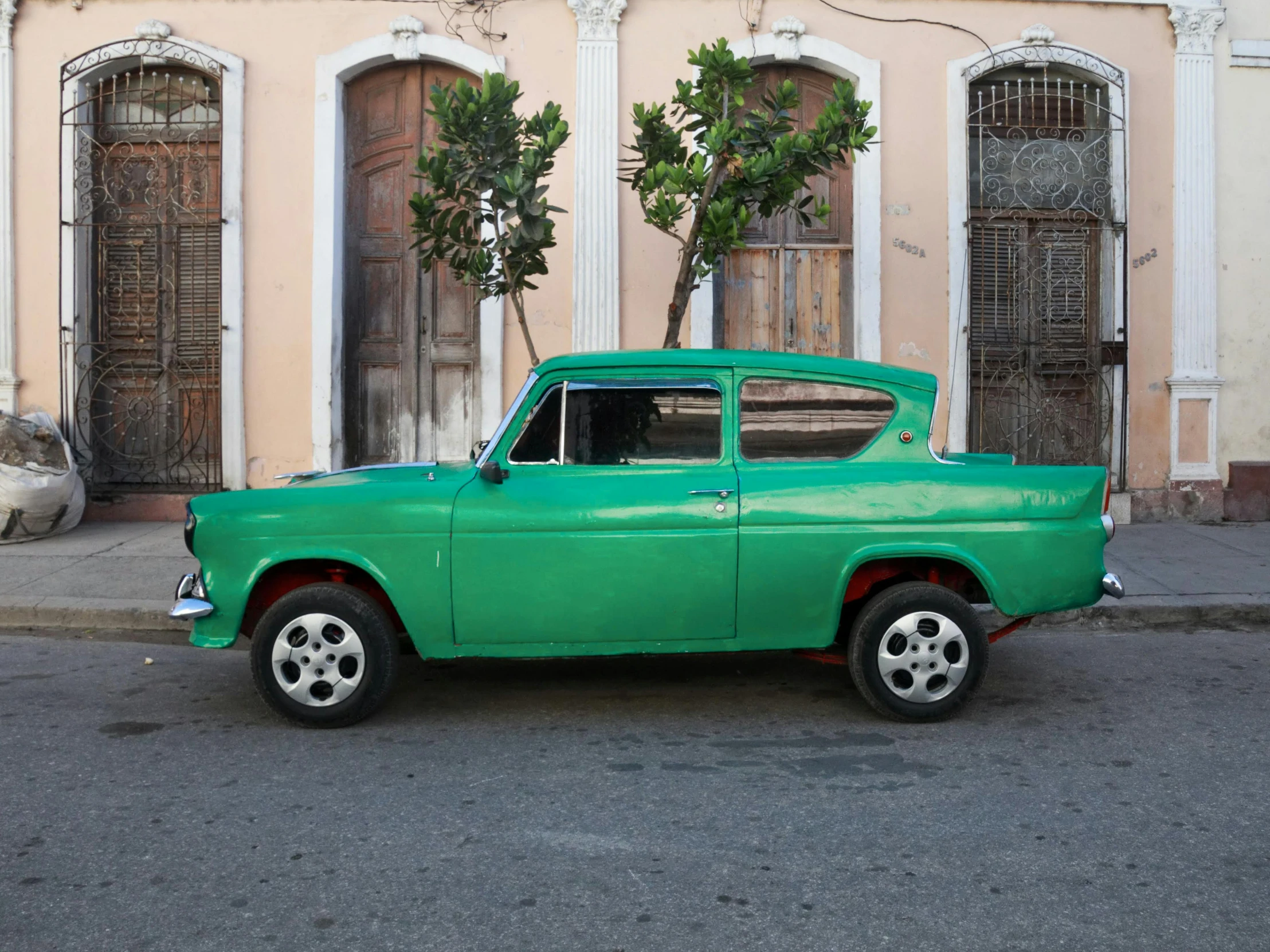 an older green car parked in front of a building