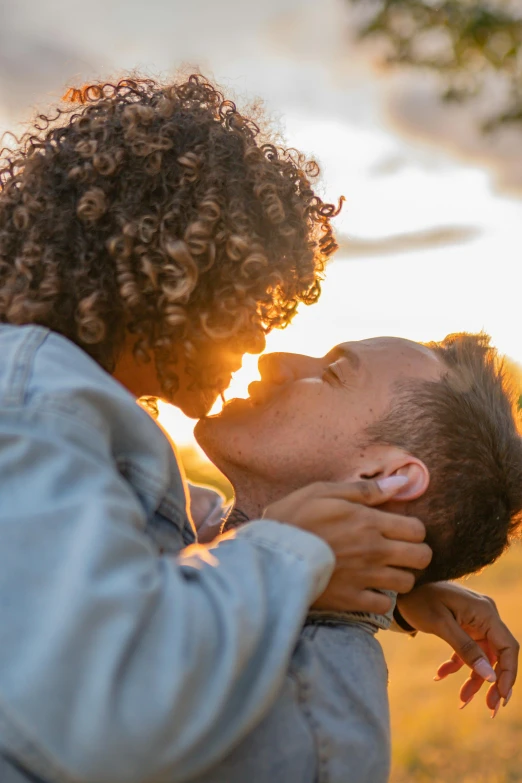 a couple kissing each other outdoors on the grass