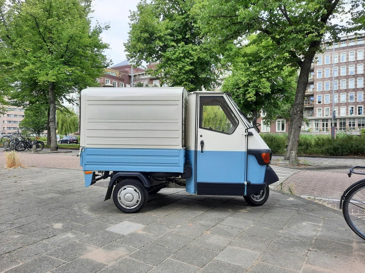 a small blue and white truck parked next to a bike