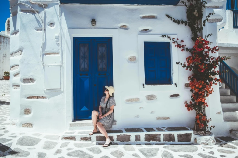 the woman is sitting on the steps near the blue doors