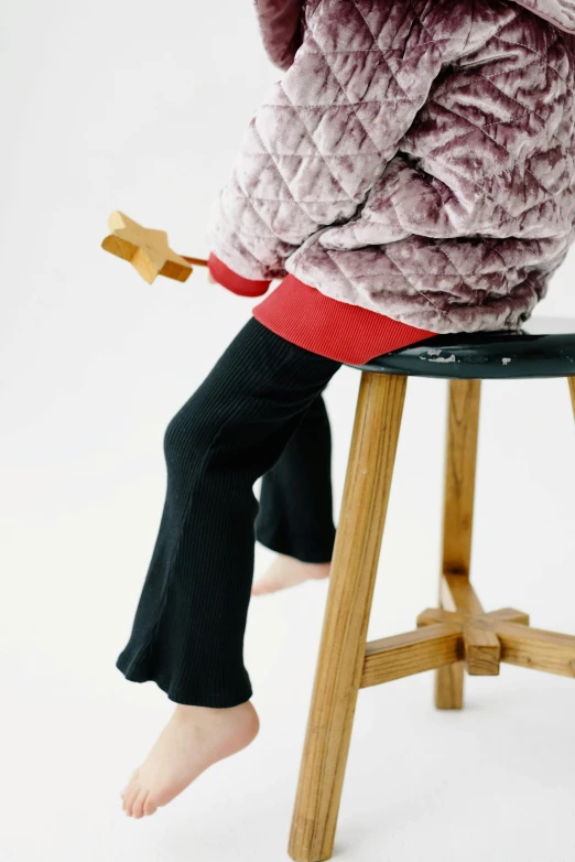 a  sitting on a stool with a toy