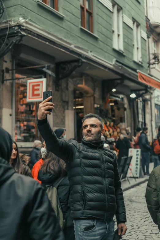 a man standing on a street holding up his cellphone