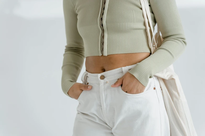 a woman wearing a green crop top is putting her pants in the pockets