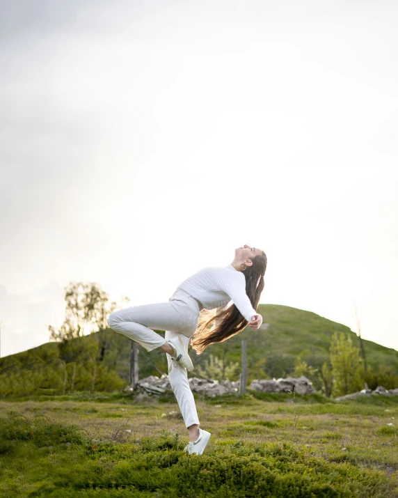 a woman is doing a yoga pose in the middle of a field