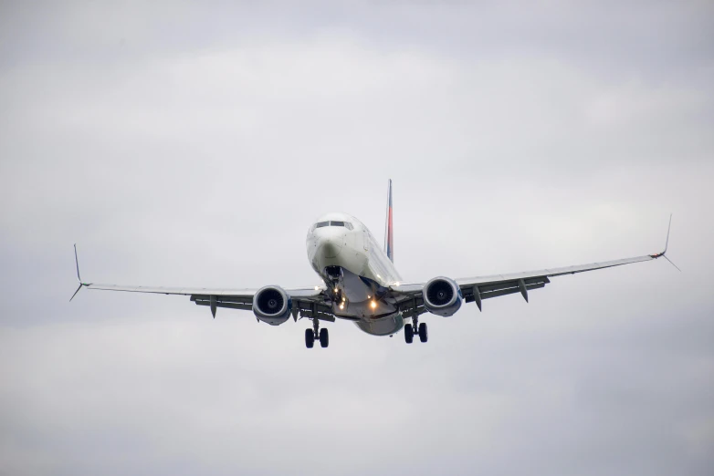 the underside of an airliner flying in a cloudy sky