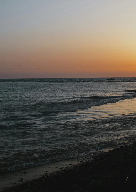 a sunrise over a beach with some surfers in the water